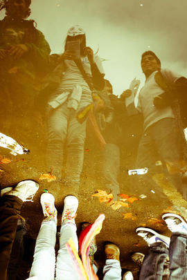 Manifestantes reflejados en charco de agua de lluvia