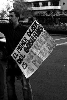 Hombre sosteniendo cartel "EL PRIMER DEBER DEL GOBIERNO ES DAR EDUCACIÓN AL PUEBLO!!"