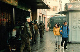 Personas caminando junto a piquete de Carabineros de Chile