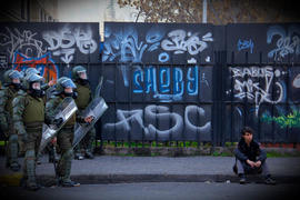 Piquete de Carabineros de Chile observando a persona sentada en el suelo