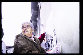 Doris Meniconi pegando afiches en el frontis de Londres 38, ex centro de detención y tortura