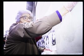 Doris Meniconi pegando afiches en el frontis de Londres 38, ex centro de detención y tortura