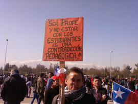 Persona sosteniendo cartel "SER PROFE Y NO ESTAR CON LOS ESTUDIANTES ES UNA CONTRADICCIÓN PEDAGÓGICA!!"