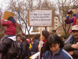 Mujer sosteniendo pancarta "ART 7: El niño tiene derecho a recibir educación gratuita y obligatoria"