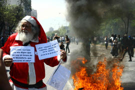 Viejito pascuero con carteles alusivos a manifestacion estudiantil