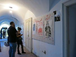 Personas observando afiches de la Brigada 40 años en exhibición en Nápoles