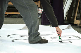 Persona pintando lienzo para la intervención urbana "Puentes de la Memoria"