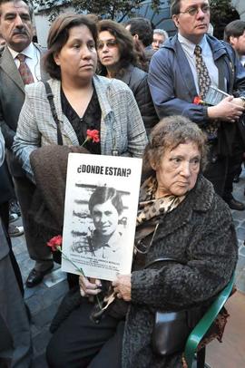 Mujer sosteniendo fotografía de Ernesto Salamanca Morales en inauguración de Memorial Londres 38
