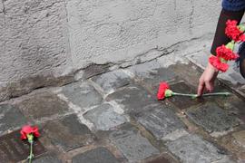 Persona dejando claveles rojos en adoquín conmemorativo de Londres 38