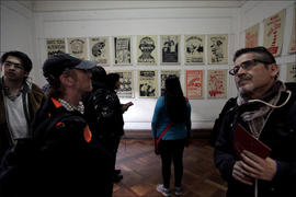 Hombre con informativo en sus manos observando exposición de afiches