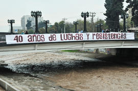 Intervención con lienzo "40 años de luchas y resistencia" en puente del río Mapocho
