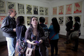 Grupo de 6 personas observando exposición de afiches