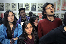 Grupo de 5 personas observando exposición de afiches