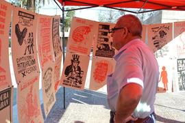 Persona observando afiches de la "Brigada 40 años de luchas y resistencia" en exhibición itinerante