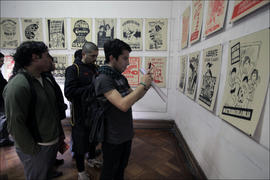 Grupo de 4 personas observando exposición de afiches