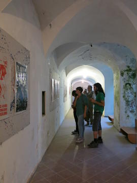 Personas observando afiches de la Brigada 40 años en exhibición en Nápoles